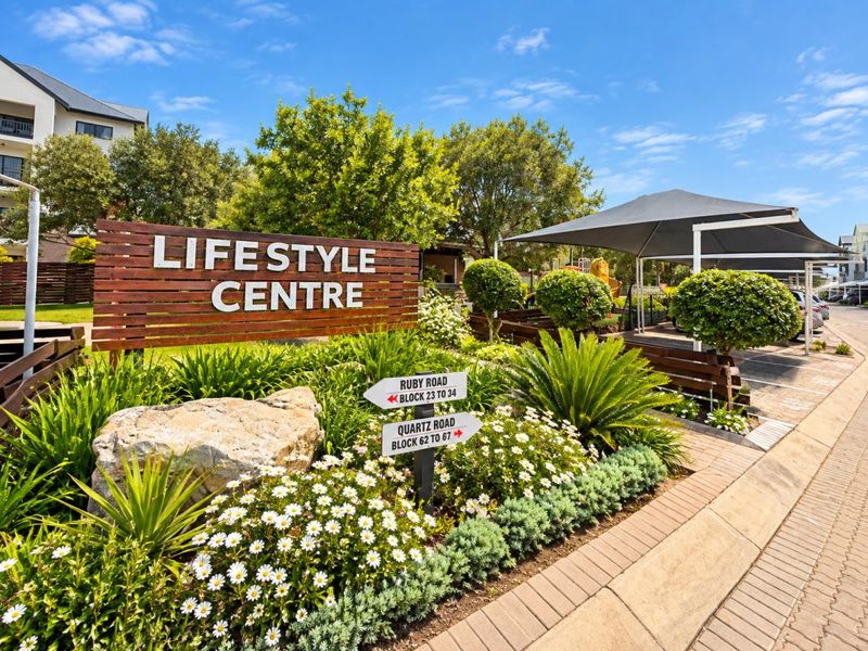 Exterior view of the apartment complex lifestyle centre featuring landscaped gardens, paved pathways, and shaded parking areas.