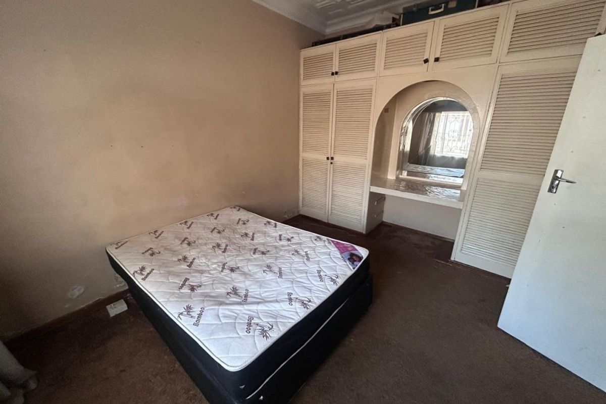 Bedroom featuring extensive built-in cabinetry with an integrated vanity mirror, carpeted flooring, and decorative ceiling cornice.