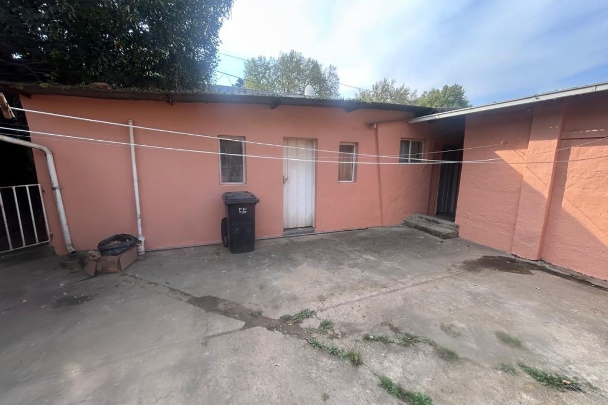 Rear exterior view of the property featuring a concrete paved courtyard area and access to the building's rear entrance.