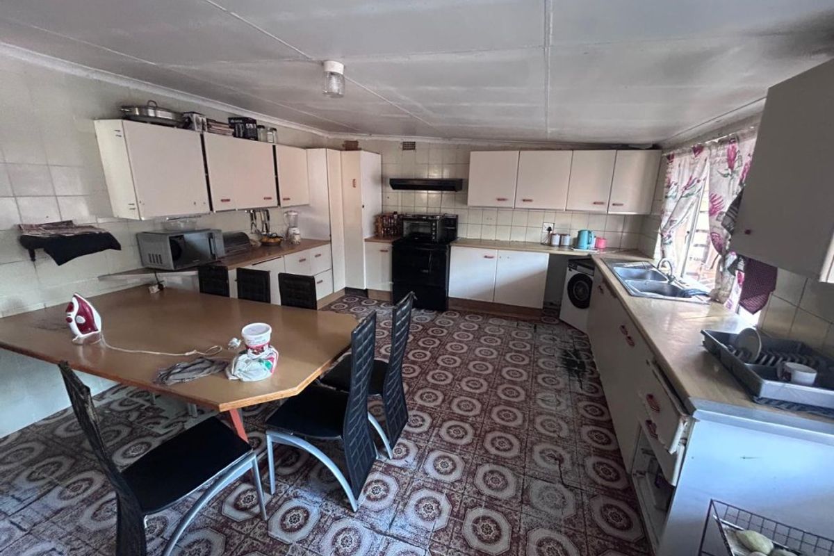 A dated kitchen featuring original cabinetry, tiled splashbacks, and a double bowl sink, offering significant potential for a modern renovation.