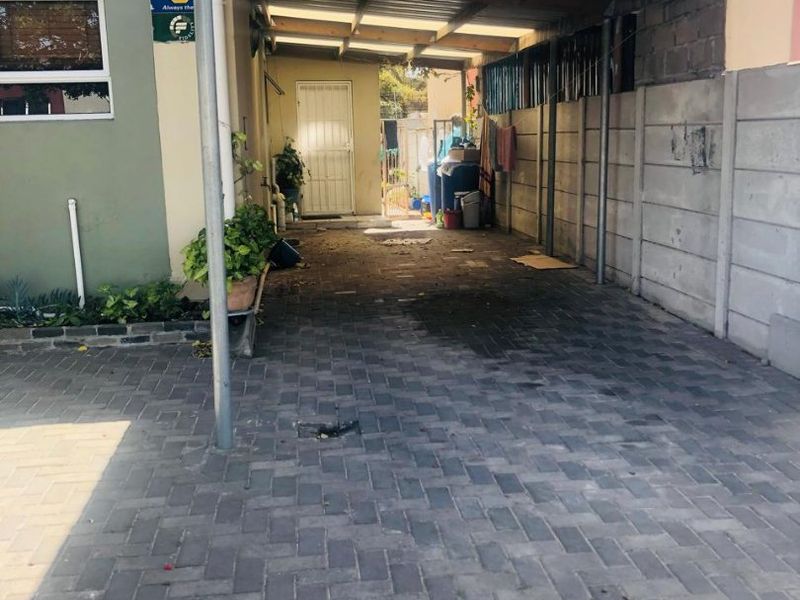 A covered carport area with paved flooring and a secure side entrance, providing functional off-street parking space.