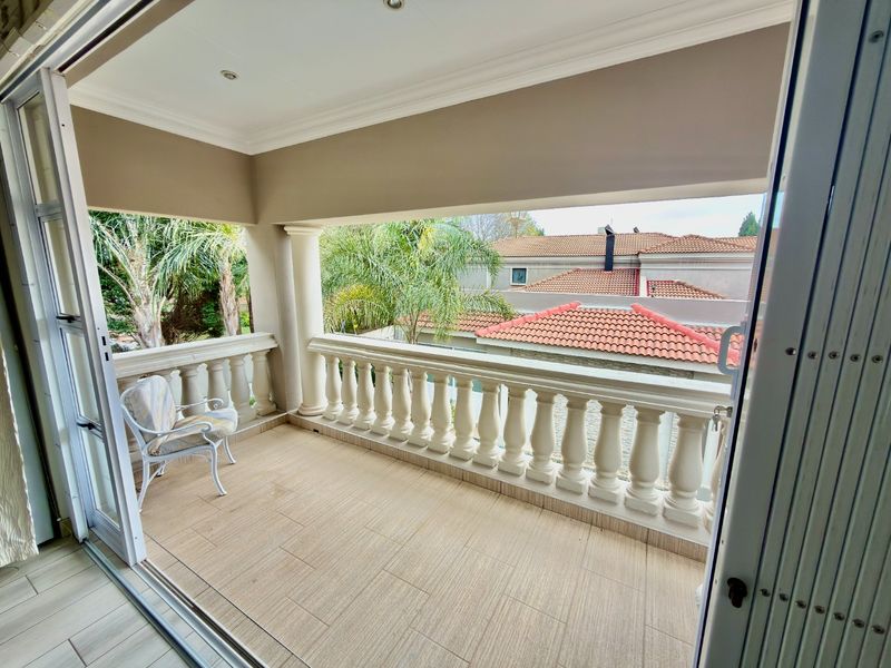 A covered balcony featuring tiled flooring, a classic balustrade, and sliding glass door access, offering an elevated outdoor space.