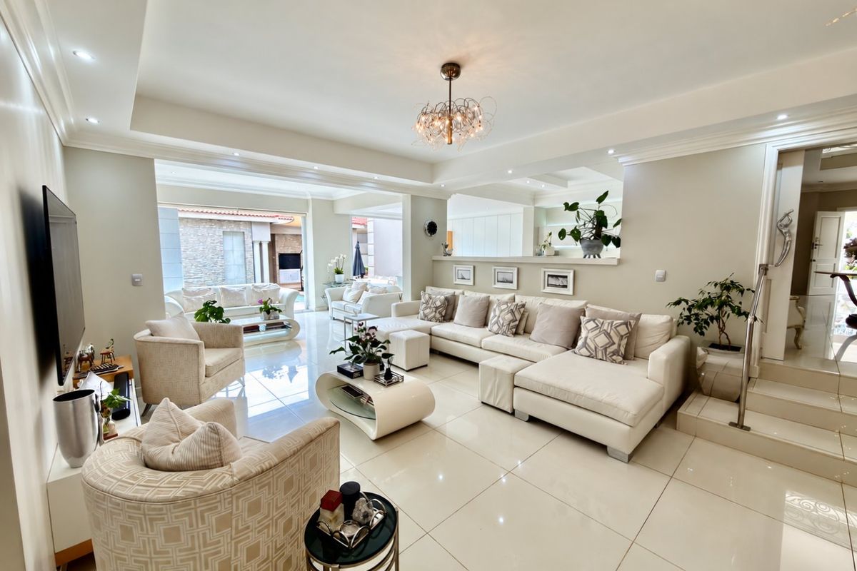Spacious, modern living room featuring polished porcelain floor tiles, recessed ceiling lighting, and an open-plan layout with a built-in half wall.