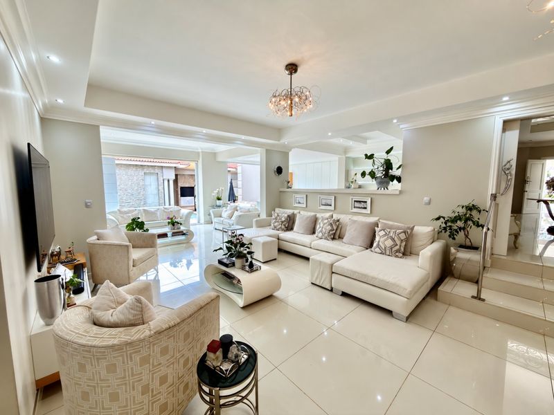 Spacious, modern living room featuring polished porcelain floor tiles, recessed ceiling lighting, and an open-plan layout with a built-in half wall.