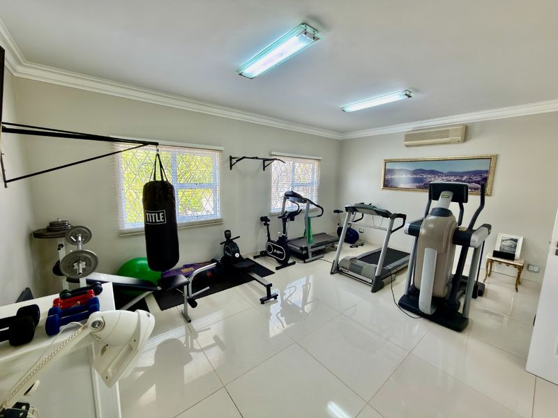 A dedicated home gym space featuring tiled flooring, split-system air conditioning, and security bars on the windows.