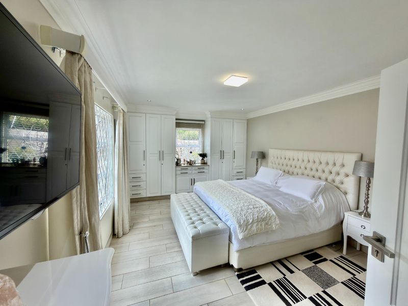 Spacious bedroom featuring extensive built-in cabinetry, neutral tiled flooring, and elegant coved cornicing, creating a bright and well-maintained living space.