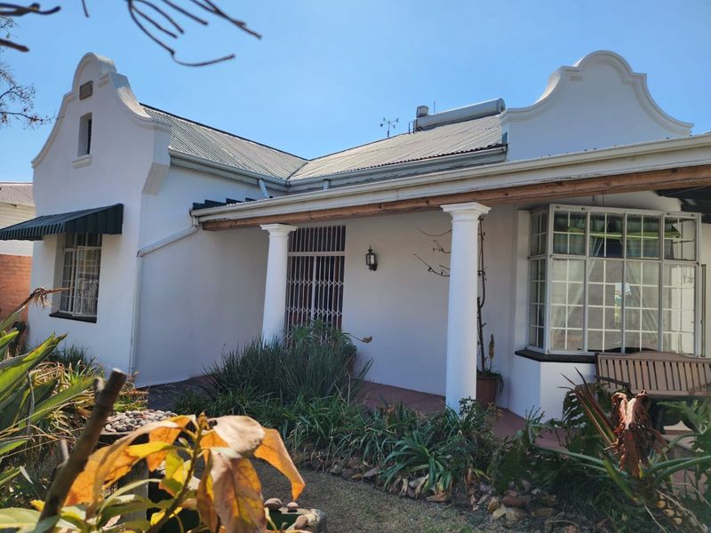 Charming Cape Dutch style home featuring a covered veranda with classical columns, a corrugated iron roof, and a solar water heating system.