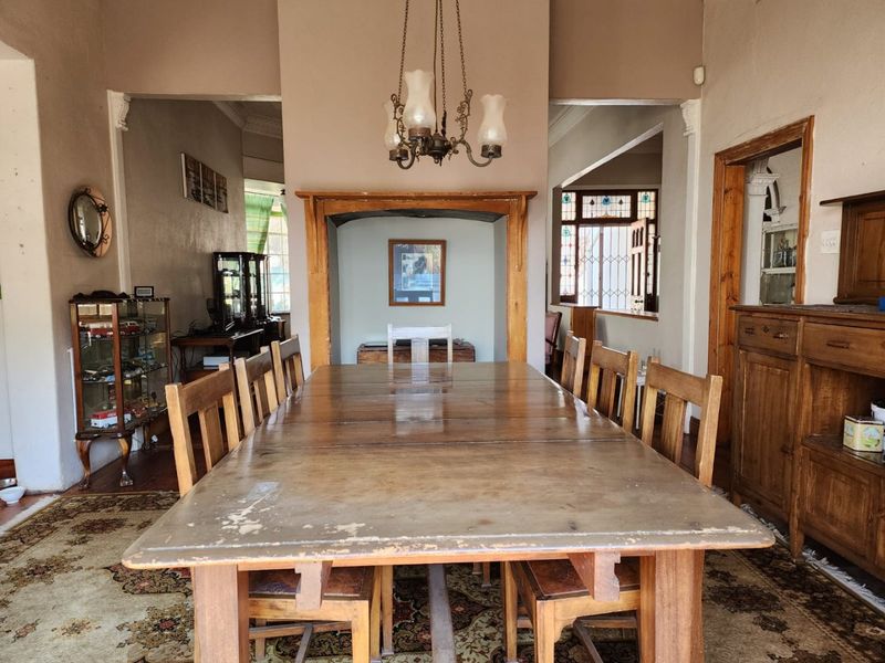 A traditional dining room featuring a central fireplace mantel, decorative chandelier, and classic architectural archways leading to adjacent living spaces.