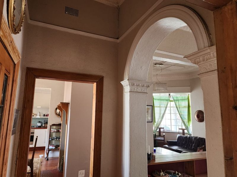 A character-filled hallway featuring a classic decorative archway, ornate ceiling moldings, and pressed metal ceilings, connecting to the main living and kitchen areas.
