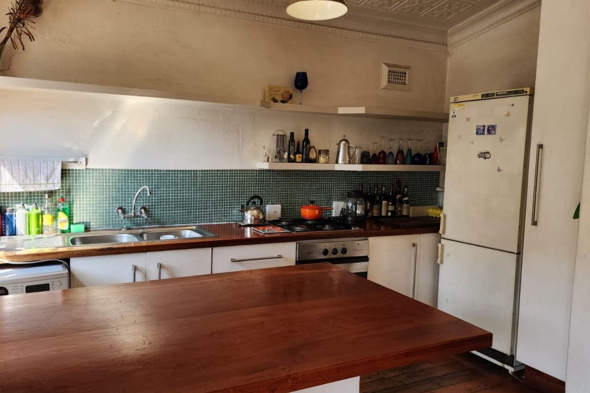 A character-filled kitchen featuring a pressed metal ceiling, timber flooring, wooden countertops, and a tiled splashback, offering a blend of vintage charm and functionality.
