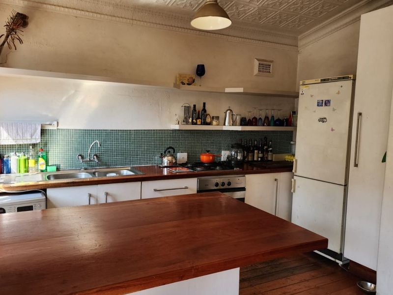 A character-filled kitchen featuring a pressed metal ceiling, timber flooring, wooden countertops, and a tiled splashback, offering a blend of vintage charm and functionality.