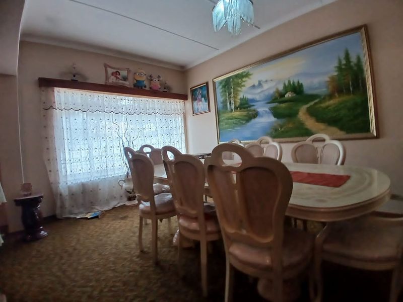 A traditional dining room featuring carpeted flooring and a large wall-mounted landscape painting.