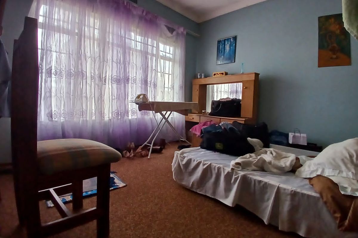 A bedroom featuring carpet flooring and a large window, currently used as a multi-purpose living space.