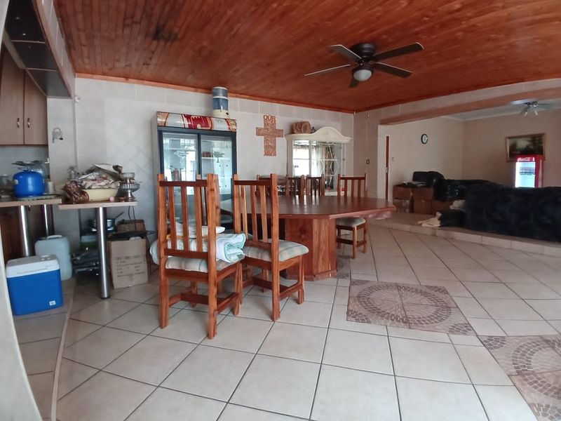 Spacious open-plan living and dining area featuring a timber-clad ceiling, ceiling fan, and ceramic tiled flooring throughout.