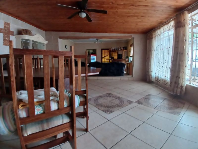 Spacious open-plan living and dining area featuring a timber-clad ceiling, ceiling fan, and tiled flooring with decorative accents.