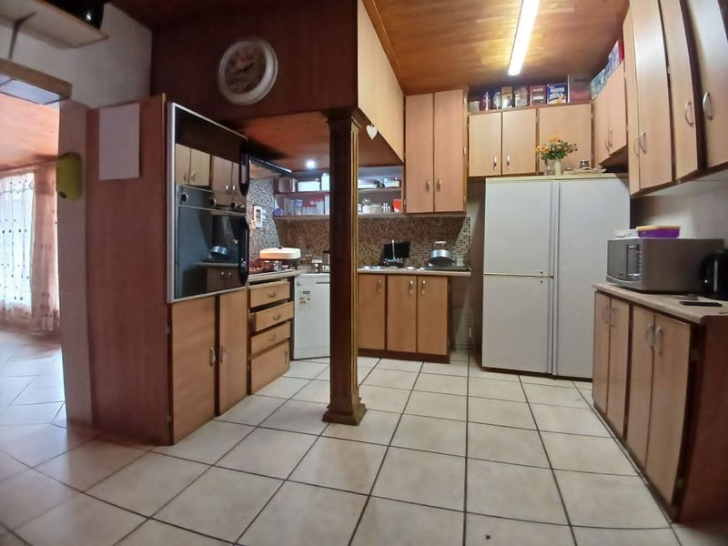 A functional kitchen featuring wooden cabinetry, mosaic tile backsplash, tiled flooring, and a built-in oven, offering a traditional layout with potential for modernization.