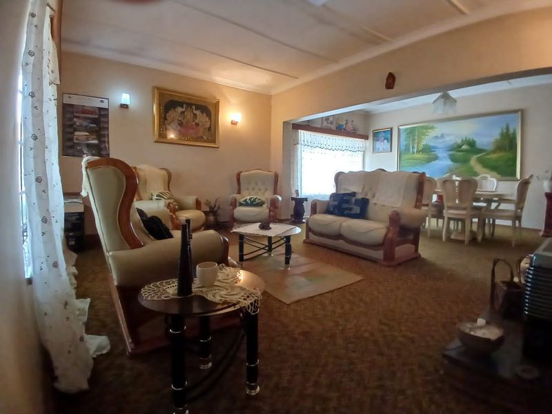 Spacious open-plan living and dining area featuring carpeted flooring and coved ceilings, offering a traditional layout with potential for modern updates.