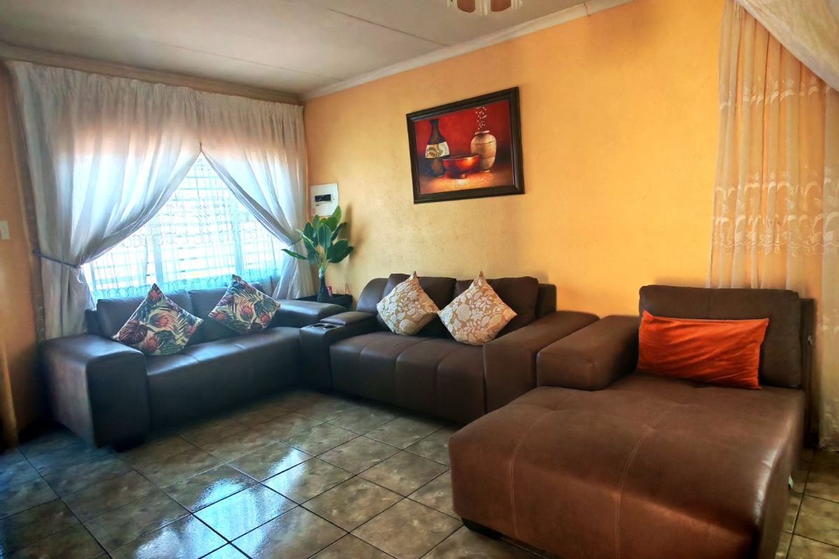 A living room featuring tiled flooring and a ceiling light fixture, requiring cosmetic updates to the walls and ceiling to improve the overall aesthetic.