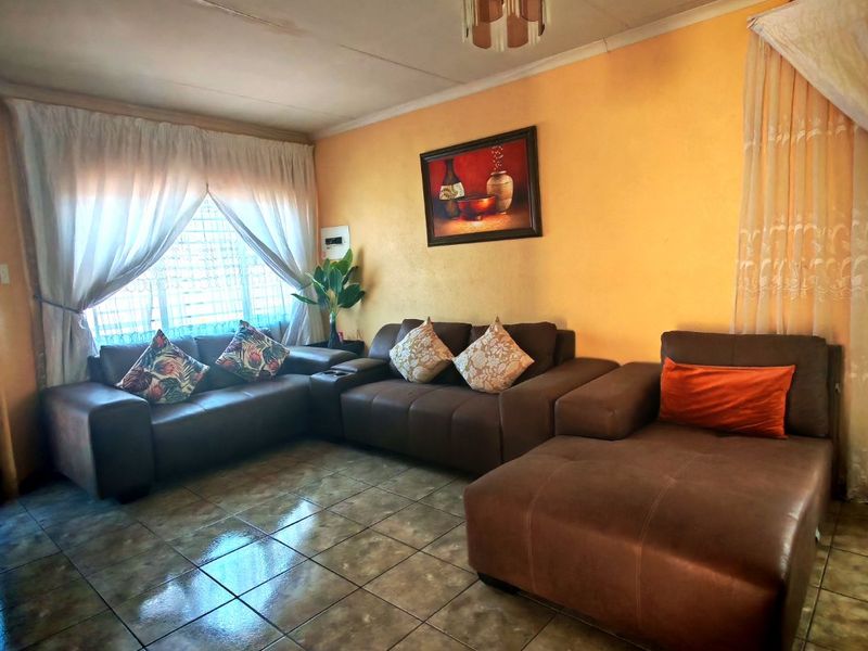 A living room featuring tiled flooring and a ceiling light fixture, requiring cosmetic updates to the walls and ceiling to improve the overall aesthetic.