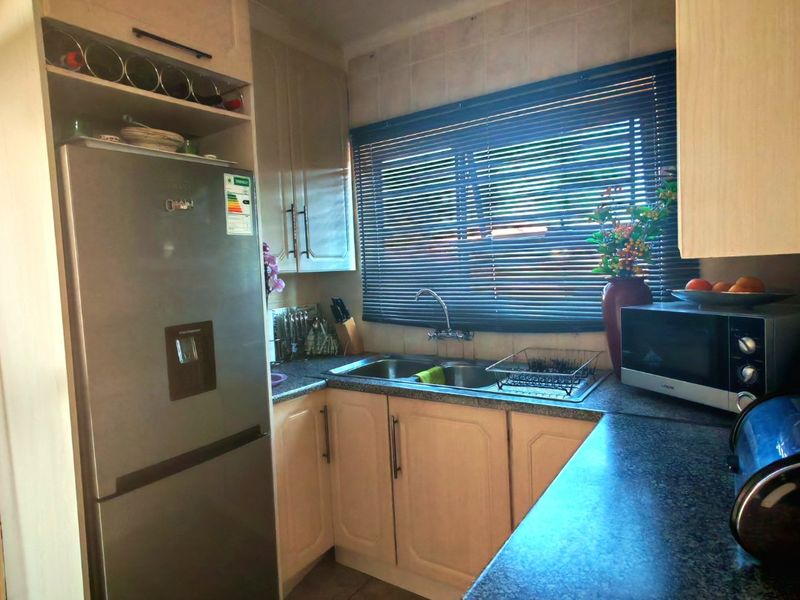 A functional kitchen featuring built-in cabinetry, laminate countertops, a double basin sink, and tiled backsplash, providing a practical workspace.