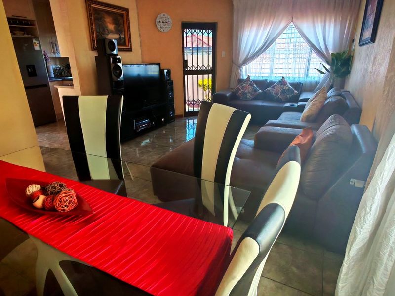 Open-plan living and dining area featuring tiled flooring and direct access to the exterior via a security gate.