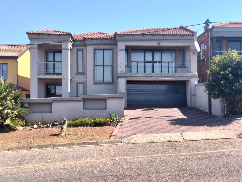 Front elevation of a double-story house featuring a double garage, upper-level balconies, and a paved driveway.