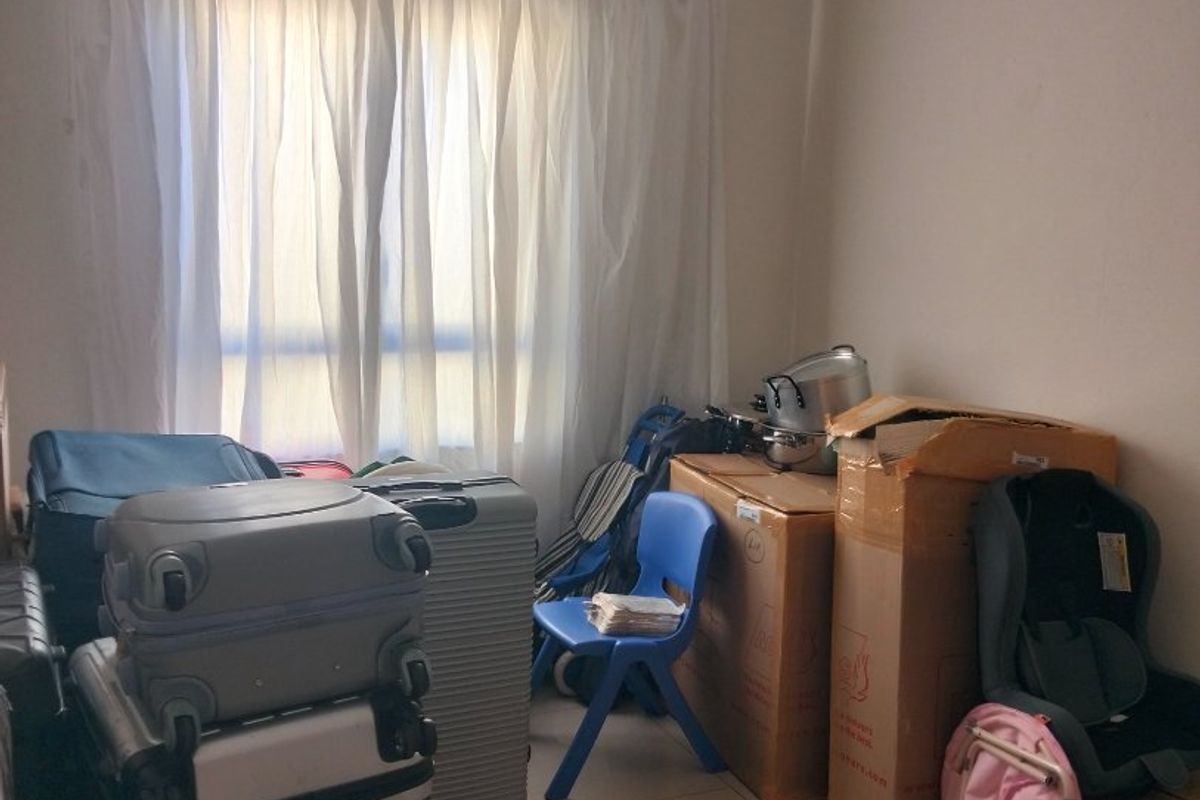 A bedroom space featuring tiled flooring and coved ceiling cornicing, currently used for storage.