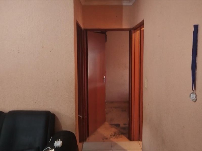 A narrow interior hallway connecting rooms, featuring dated wall finishes and tiled flooring in need of maintenance and cosmetic updates.
