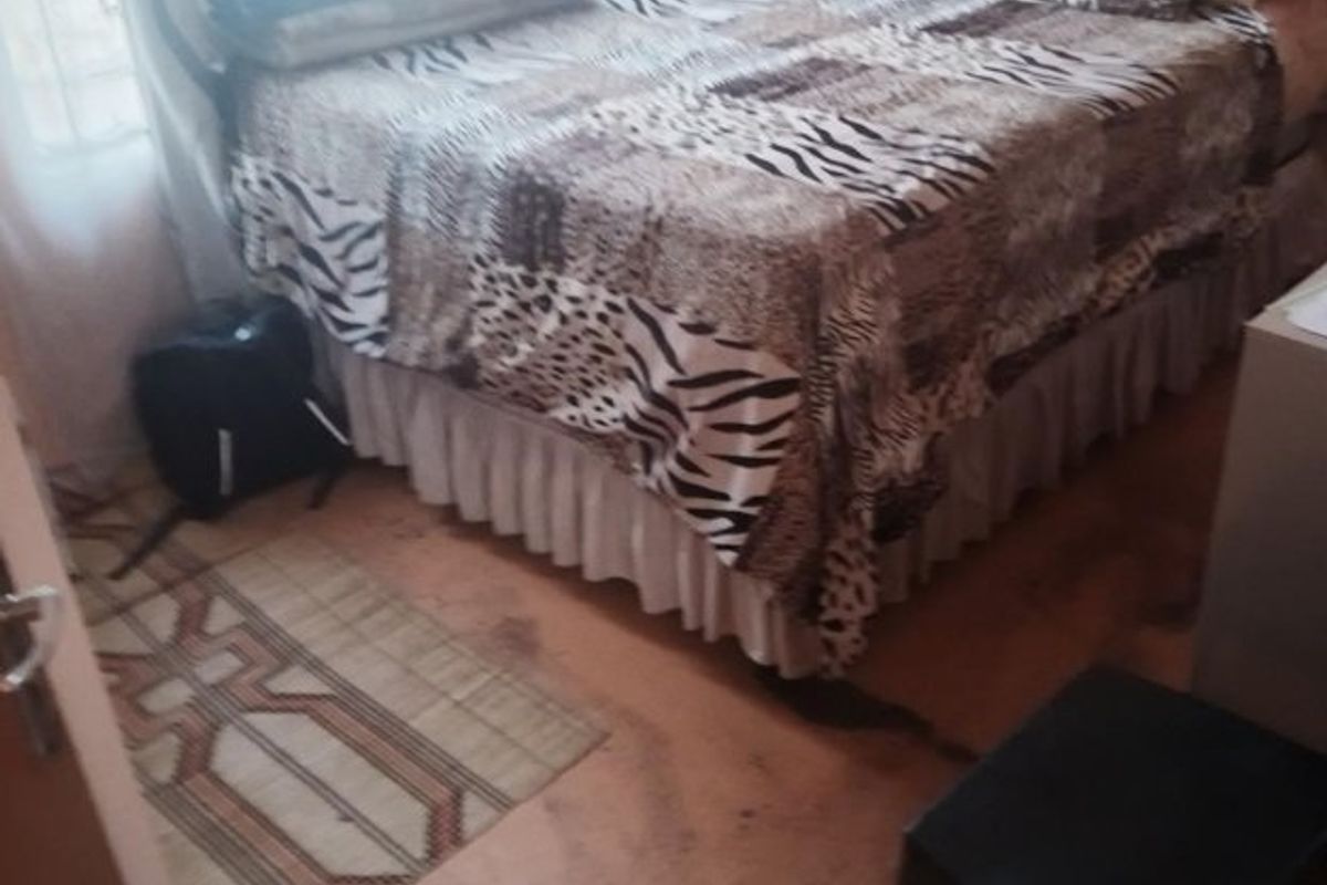A bedroom featuring basic finishes and flooring that shows significant signs of wear and staining, requiring maintenance or replacement.