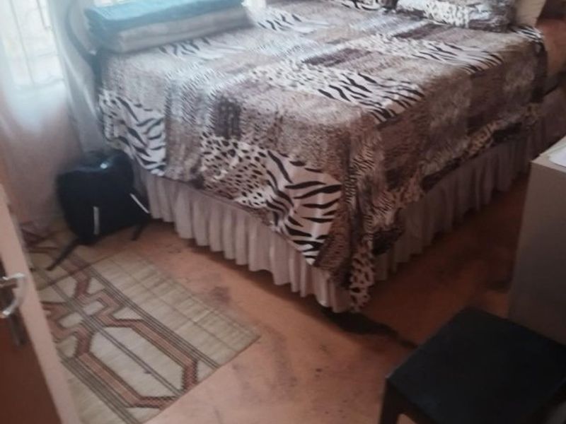A bedroom featuring basic finishes and flooring that shows significant signs of wear and staining, requiring maintenance or replacement.