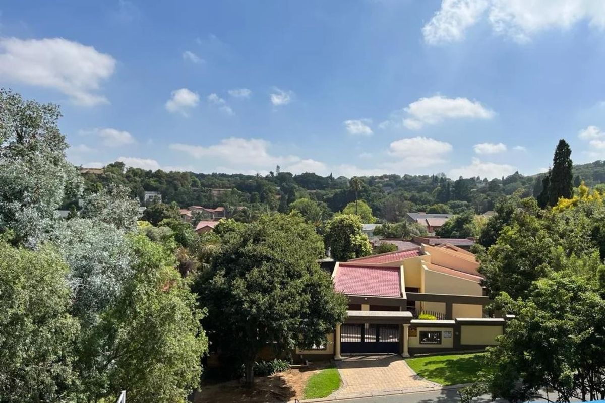 Elevated view overlooking a residential neighbourhood with lush greenery, mature trees, and a clear view of the surrounding suburban landscape.