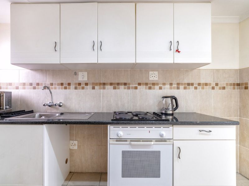 A functional kitchen featuring white cabinetry, granite countertops, a tiled backsplash, and integrated electric cooking appliances.