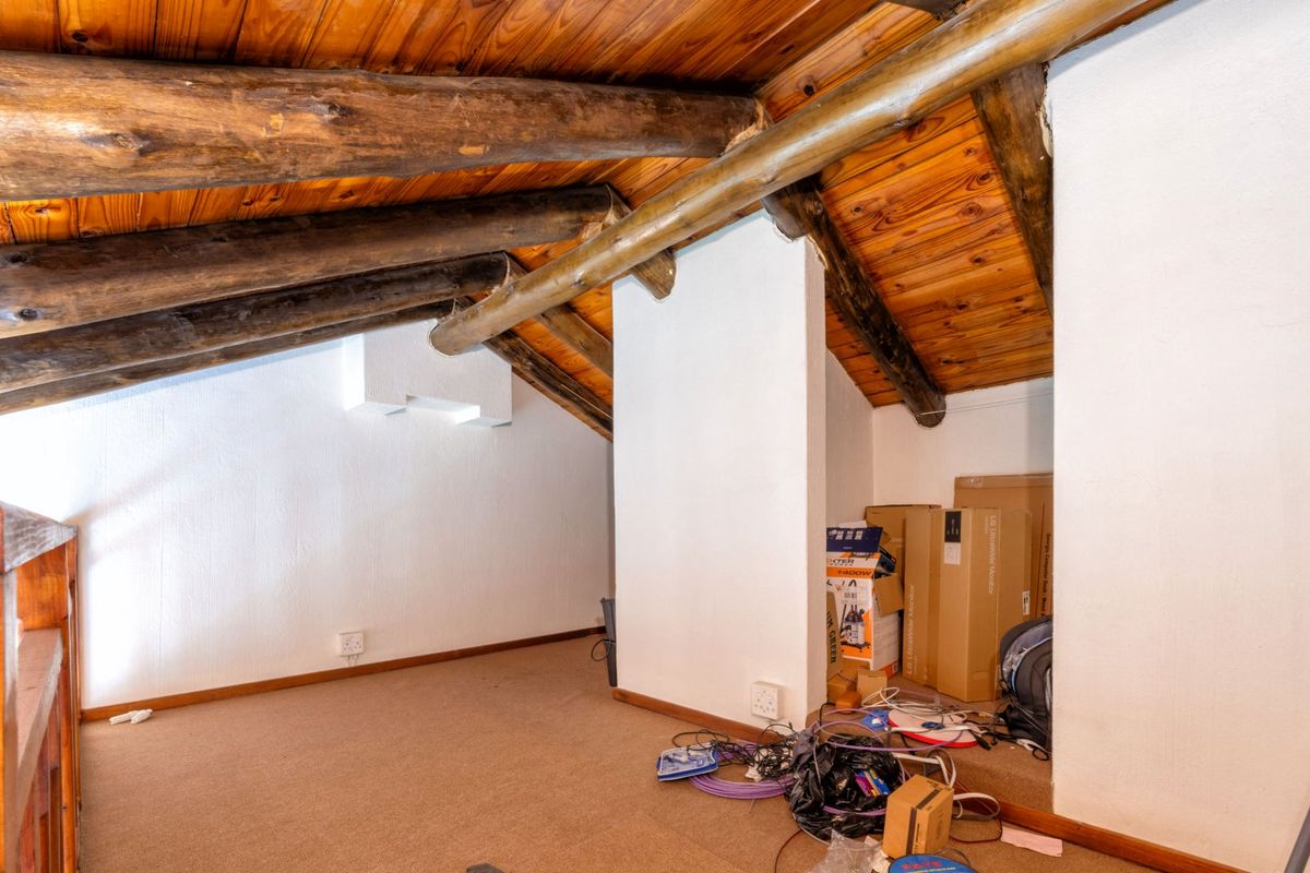 An attic-style bedroom featuring exposed timber rafters and a sloped ceiling, offering a unique architectural space ready for renovation or creative use.