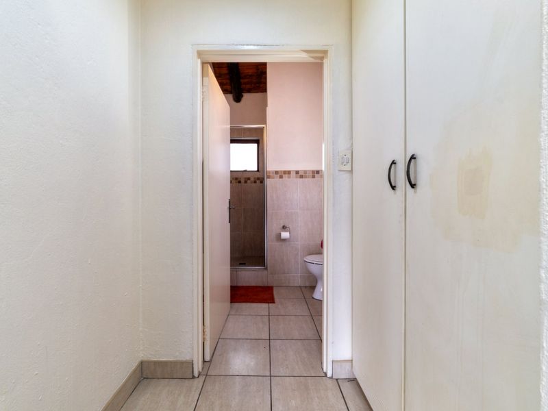 A functional hallway featuring built-in storage cupboards and tiled flooring, providing direct access to an adjacent bathroom.