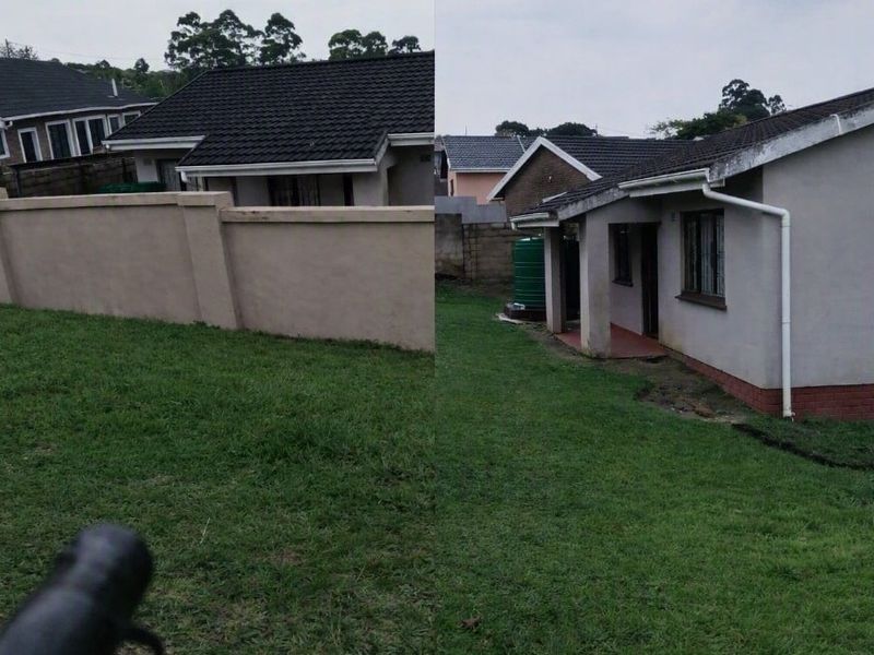 Rear view of the property featuring a lawn, perimeter wall, and rainwater guttering system.