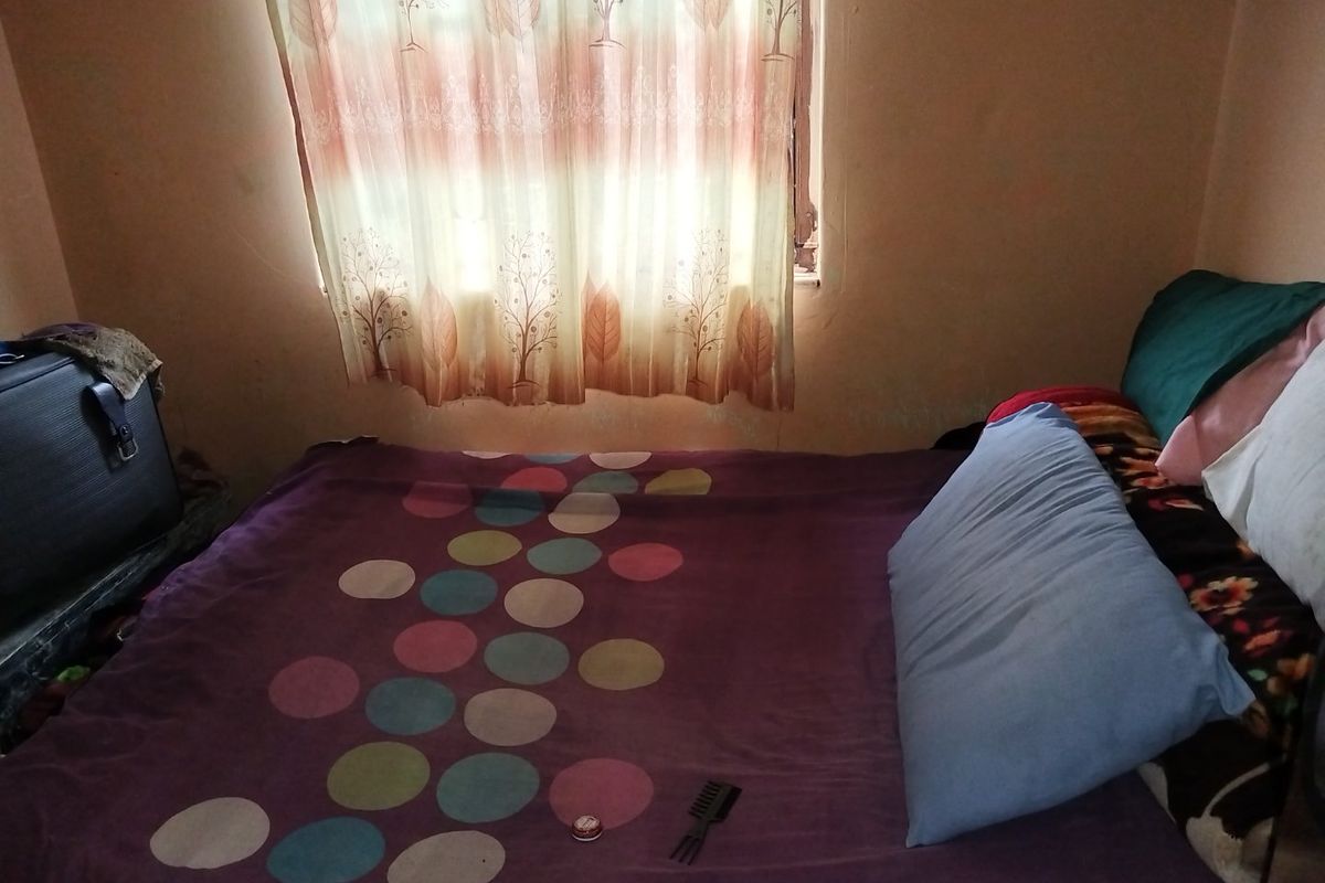 A bedroom featuring a window with curtains, showing signs of wall wear and requiring cosmetic updates.