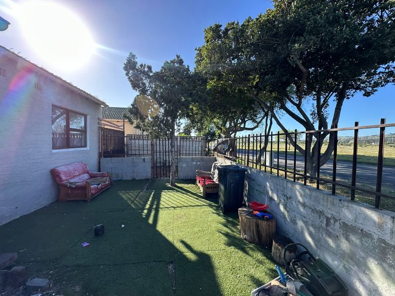 A rear outdoor area featuring a concrete boundary wall with metal fencing and artificial turf, offering potential for landscaping and improvement.