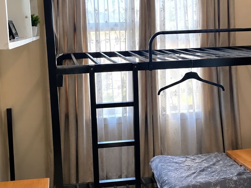 A bedroom featuring built-in shelving and a window with curtains.