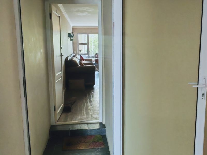 Entrance area featuring dark tiled flooring and a white aluminium frame door with a transom window, leading into the main living space.