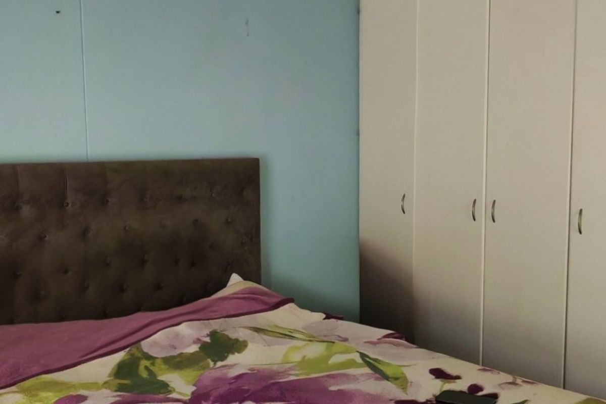 A bedroom featuring a built-in wardrobe with white doors and a flush mount ceiling light fixture.