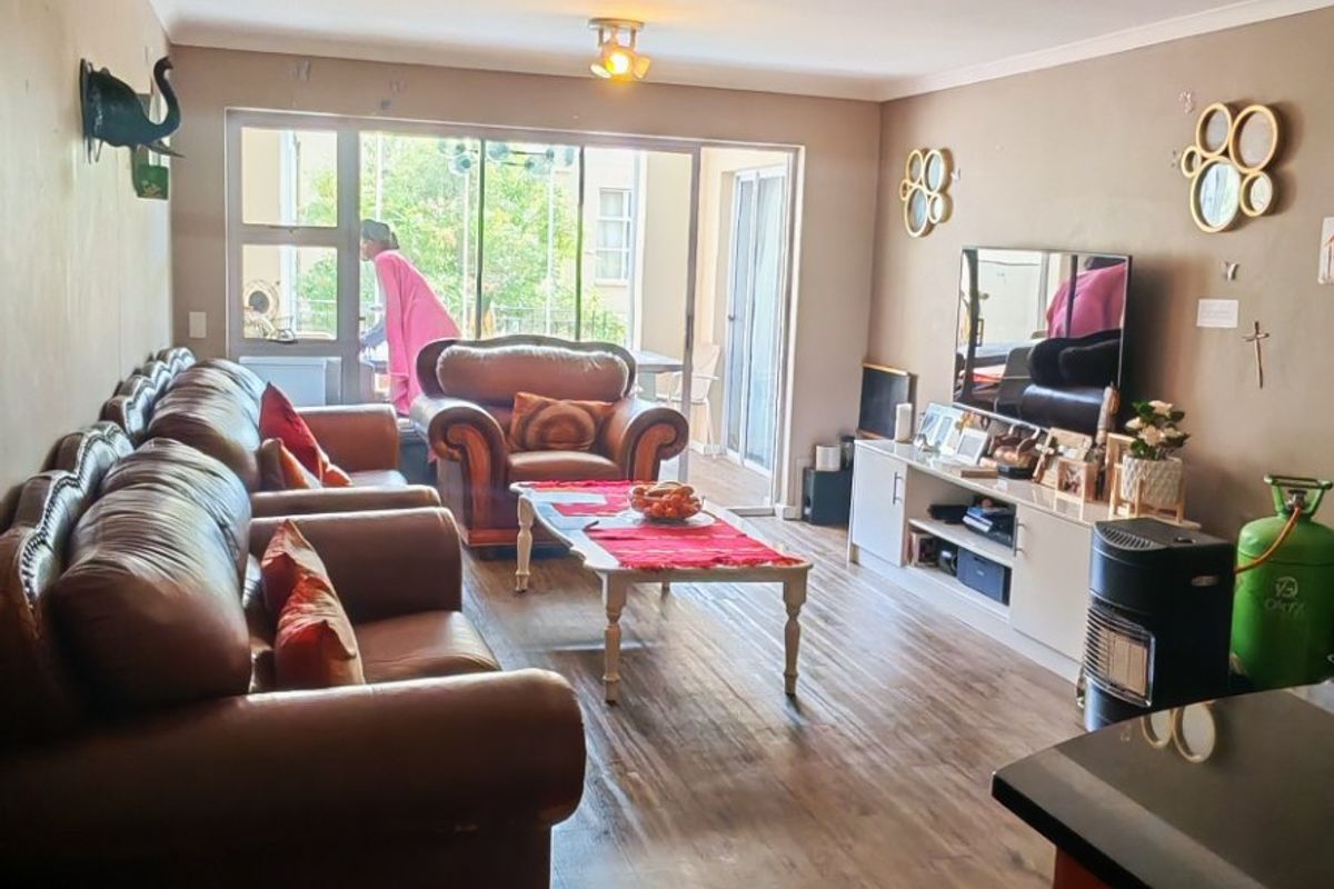 A spacious living room featuring laminate flooring, neutral wall tones, and a large sliding glass door providing access to the outdoor area.