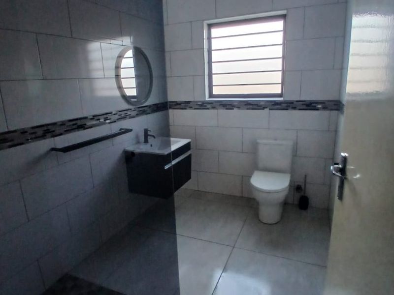 A modern, clean bathroom featuring a glass shower enclosure, wall-mounted vanity, and neutral tiled finishes throughout.