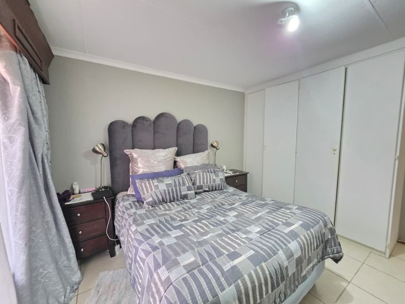 A functional bedroom featuring built-in cupboards, tiled flooring, and a central ceiling light fixture.