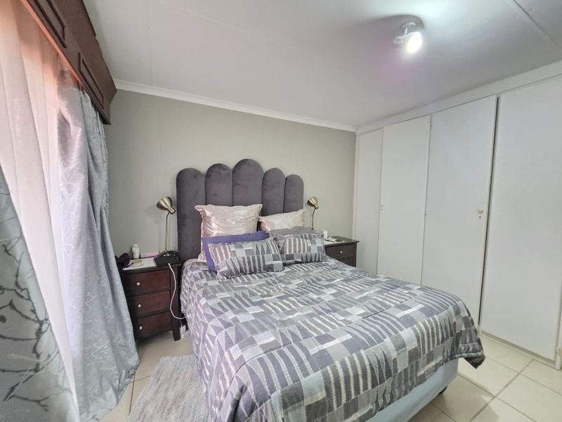 A functional bedroom featuring built-in cupboards, tiled flooring, and neutral wall finishes, providing a clean and practical living space.