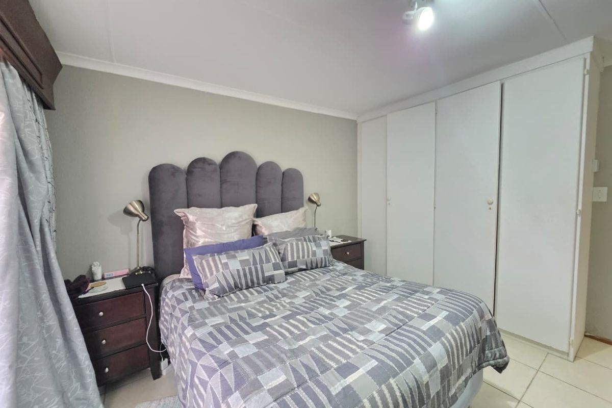 A functional bedroom featuring built-in cupboards, tiled flooring, and neutral wall finishes, providing a clean and practical living space.