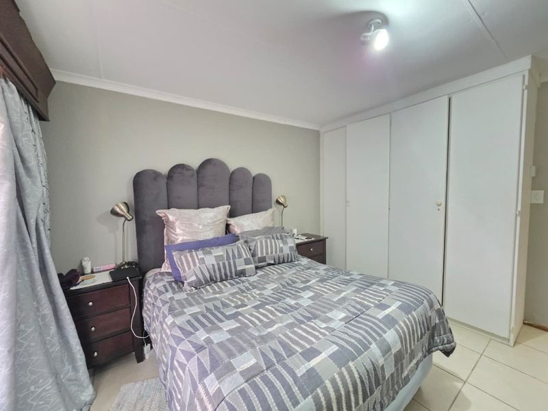 A functional bedroom featuring built-in cupboards, tiled flooring, and neutral wall finishes, providing a clean and practical living space.