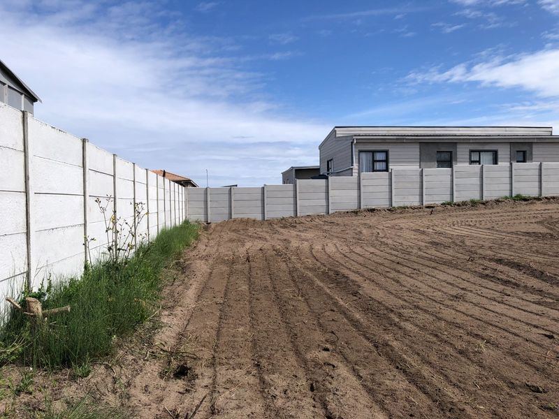 A vacant residential plot featuring cleared earth and secure precast concrete boundary walls, ready for development.