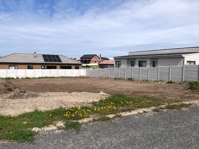 A vacant residential plot of land enclosed by precast concrete boundary walls, situated in a developed neighborhood.