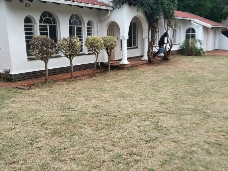 Rear view of a two-story house featuring a terracotta tiled roof, arched windows, and a covered porch area with decorative columns.