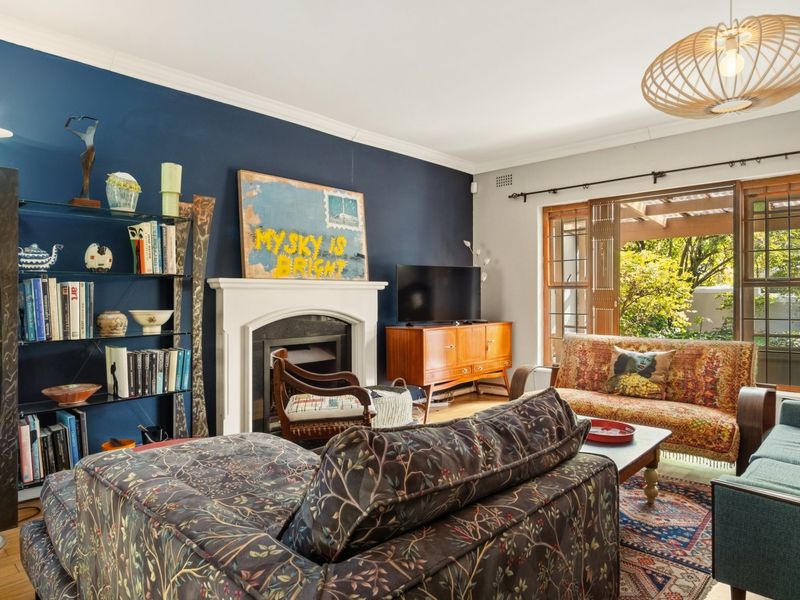 A comfortable living room featuring a fireplace, hardwood flooring, and large timber-framed sliding doors providing access to the outdoor area.